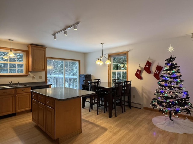 kitchen with an inviting chandelier, sink, a kitchen island, decorative light fixtures, and light hardwood / wood-style floors