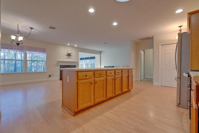 kitchen with stainless steel refrigerator, a center island, a chandelier, and light wood-type flooring