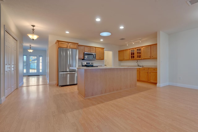 kitchen with pendant lighting, a center island, sink, light hardwood / wood-style flooring, and stainless steel appliances