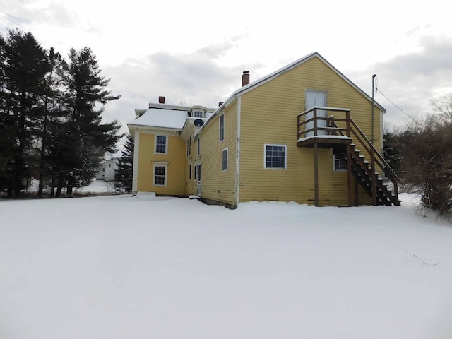 snow covered rear of property featuring a balcony