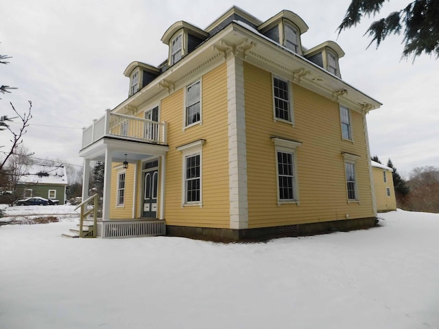 snow covered property featuring a balcony and a porch