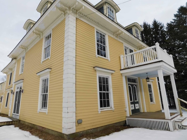 view of snowy exterior featuring a balcony and covered porch