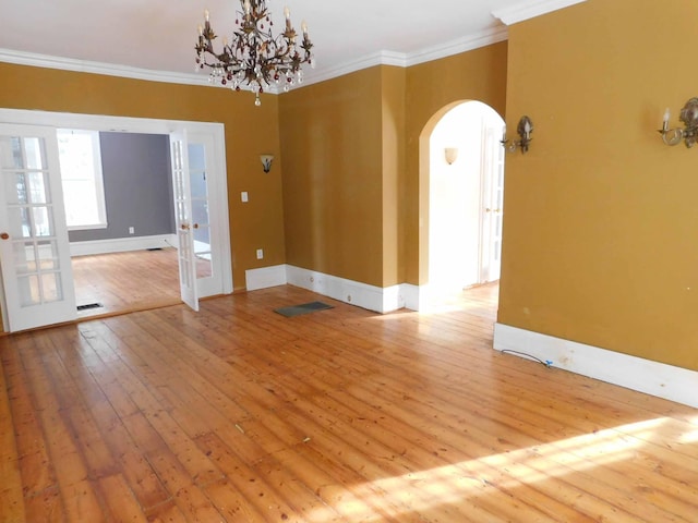 spare room featuring a chandelier, french doors, light hardwood / wood-style floors, and crown molding