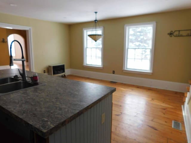 kitchen featuring a healthy amount of sunlight, sink, light hardwood / wood-style floors, and hanging light fixtures