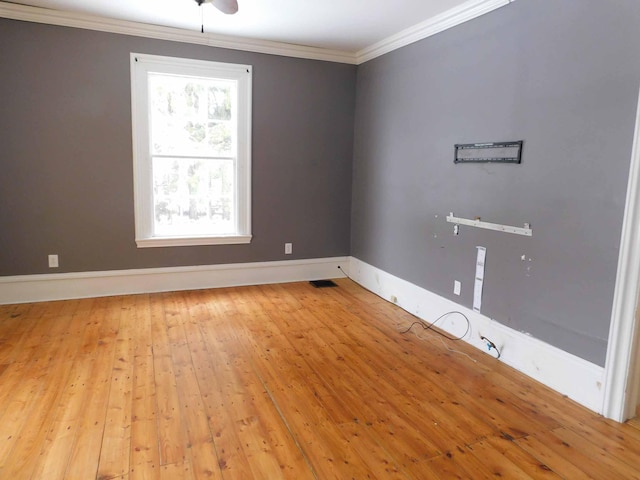 empty room featuring light wood-type flooring and ornamental molding