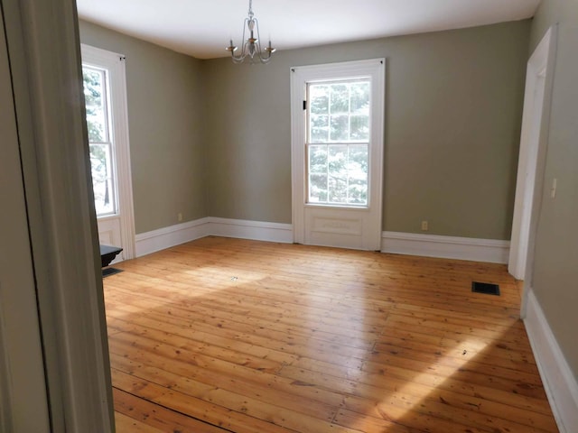 unfurnished room with a notable chandelier and light hardwood / wood-style flooring