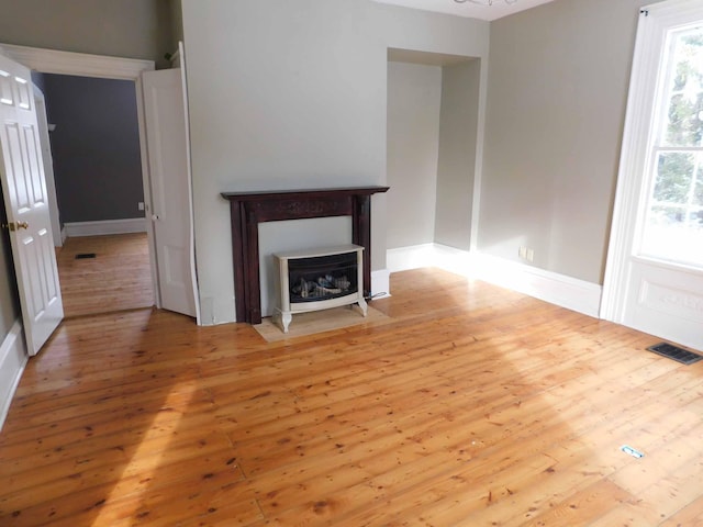 unfurnished living room featuring a chandelier and light hardwood / wood-style floors