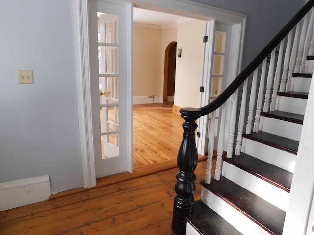 stairs with hardwood / wood-style floors and ornamental molding