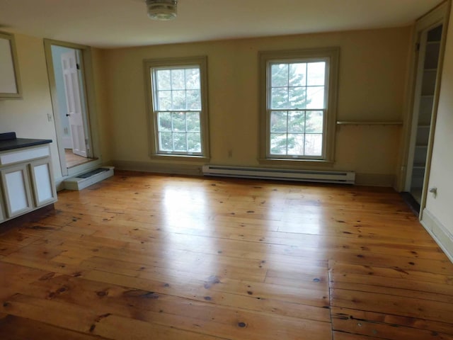 interior space with a wealth of natural light, light wood-type flooring, and baseboard heating