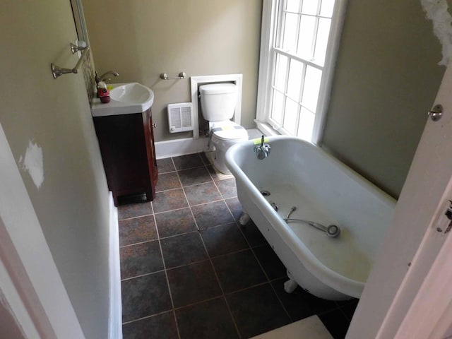 bathroom featuring a washtub, vanity, tile patterned flooring, and toilet