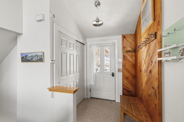 entryway with a textured ceiling, carpet floors, and vaulted ceiling