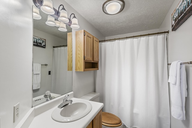 bathroom with vanity, toilet, and a textured ceiling