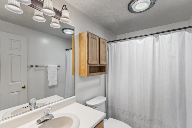 bathroom with vanity, toilet, and a textured ceiling