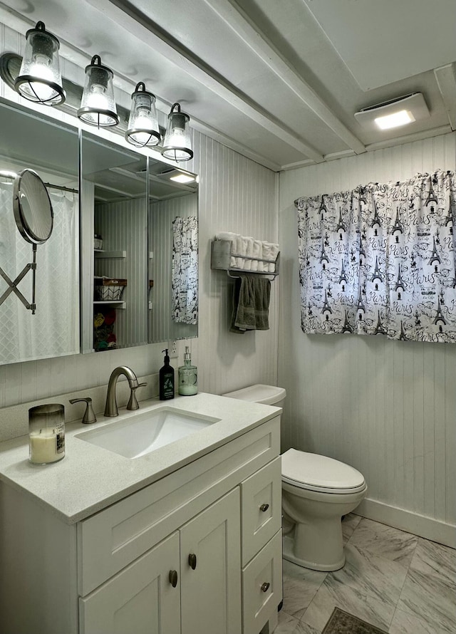 bathroom with vanity, wood walls, and toilet