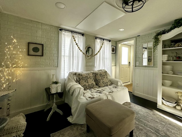 sitting room with dark hardwood / wood-style floors and brick wall