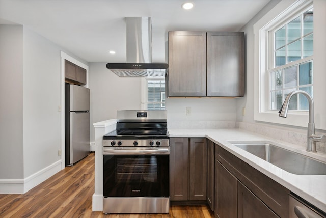 kitchen featuring a healthy amount of sunlight, stainless steel appliances, wall chimney exhaust hood, and sink