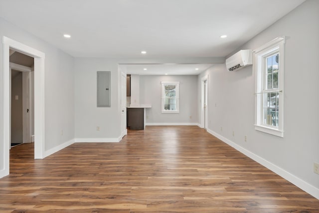 unfurnished living room featuring an AC wall unit, dark wood-type flooring, and electric panel