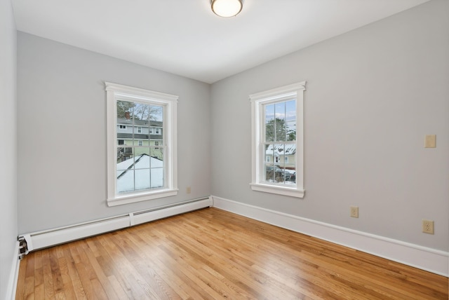 unfurnished room featuring a wealth of natural light, hardwood / wood-style floors, and a baseboard heating unit