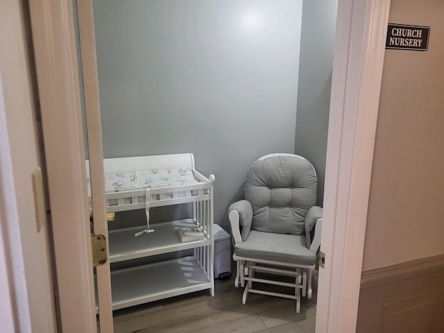 bedroom featuring wood-type flooring and a nursery area