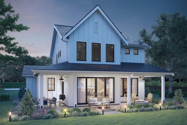 back house at dusk with a porch and a yard