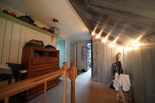 interior space featuring carpet flooring, wood walls, and vaulted ceiling