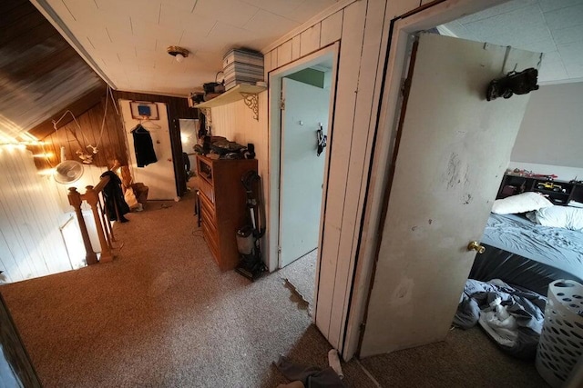 hallway featuring wooden walls, light colored carpet, and vaulted ceiling