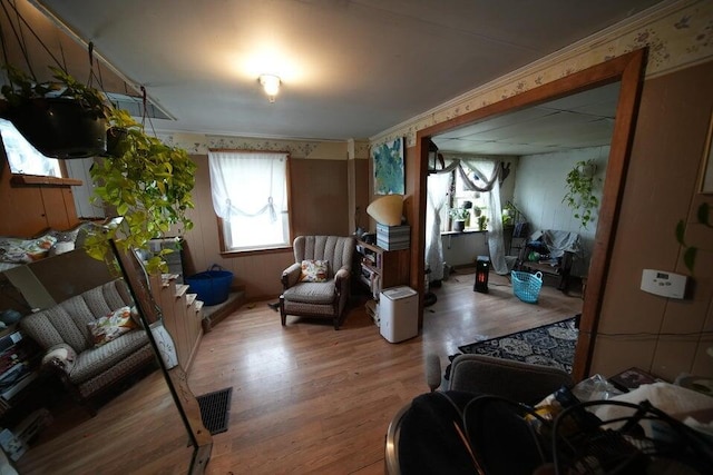 living area with crown molding and light hardwood / wood-style flooring