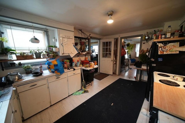 kitchen with white cabinetry, hanging light fixtures, and light hardwood / wood-style flooring