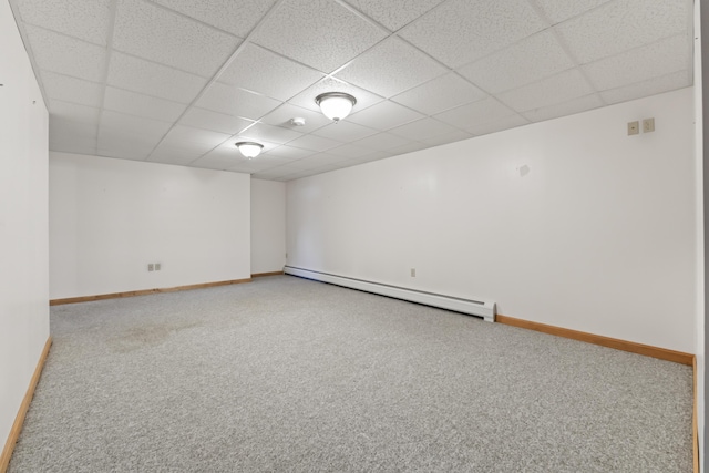 carpeted empty room with a baseboard radiator and a drop ceiling