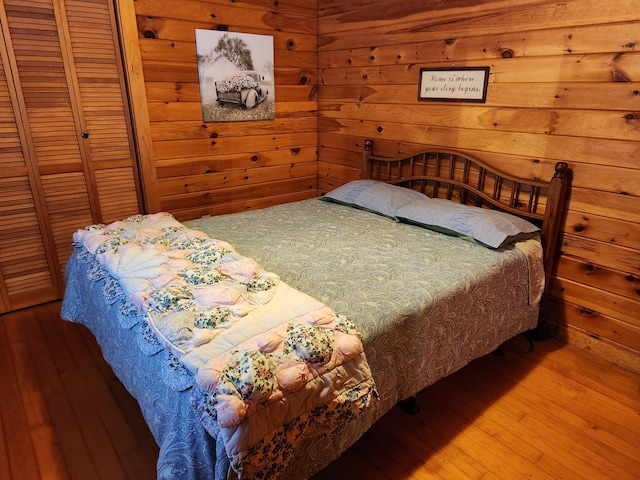 bedroom with hardwood / wood-style floors, wooden walls, and a closet