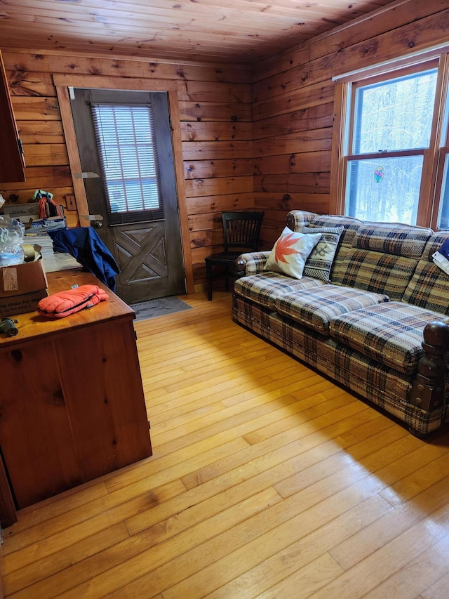 living room with wooden walls, light hardwood / wood-style floors, and wooden ceiling