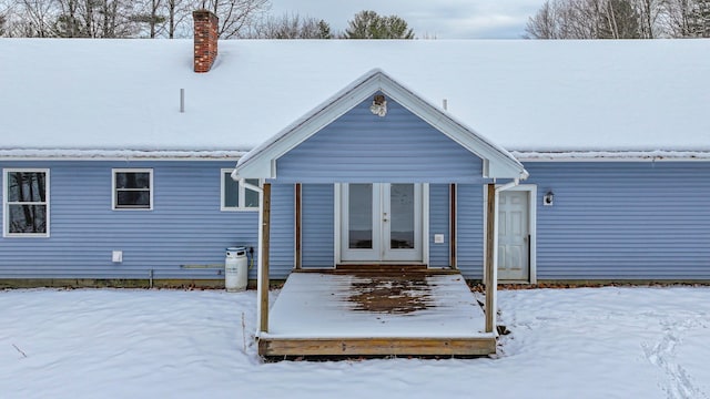 snow covered house featuring french doors