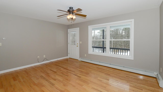 empty room featuring ceiling fan, a baseboard heating unit, and light wood-type flooring