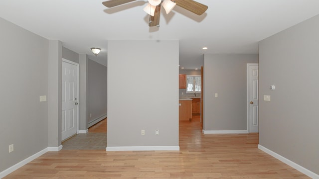 spare room with ceiling fan, light wood-type flooring, and baseboard heating