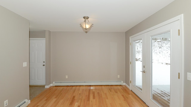 unfurnished room featuring french doors, light hardwood / wood-style flooring, and a baseboard heating unit