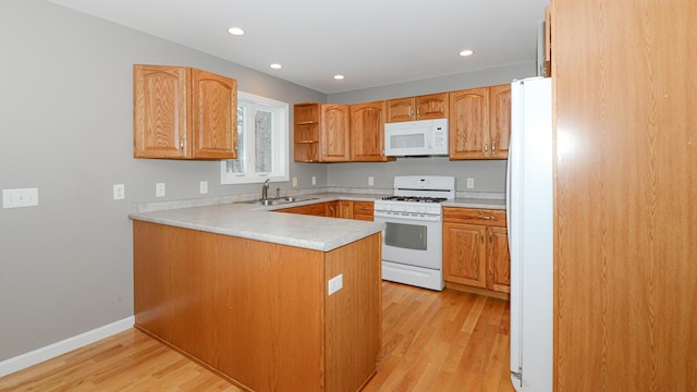 kitchen with kitchen peninsula, sink, light hardwood / wood-style floors, and white appliances