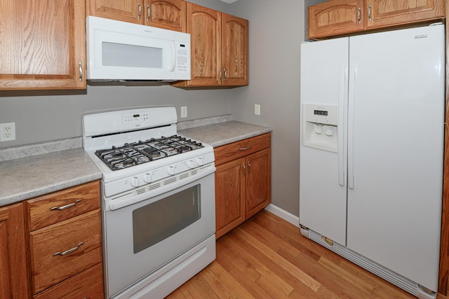 kitchen with white appliances and light hardwood / wood-style flooring