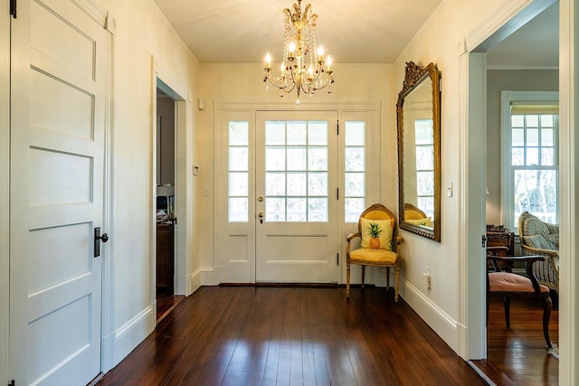 entryway featuring a chandelier, dark wood-type flooring, crown molding, and a healthy amount of sunlight