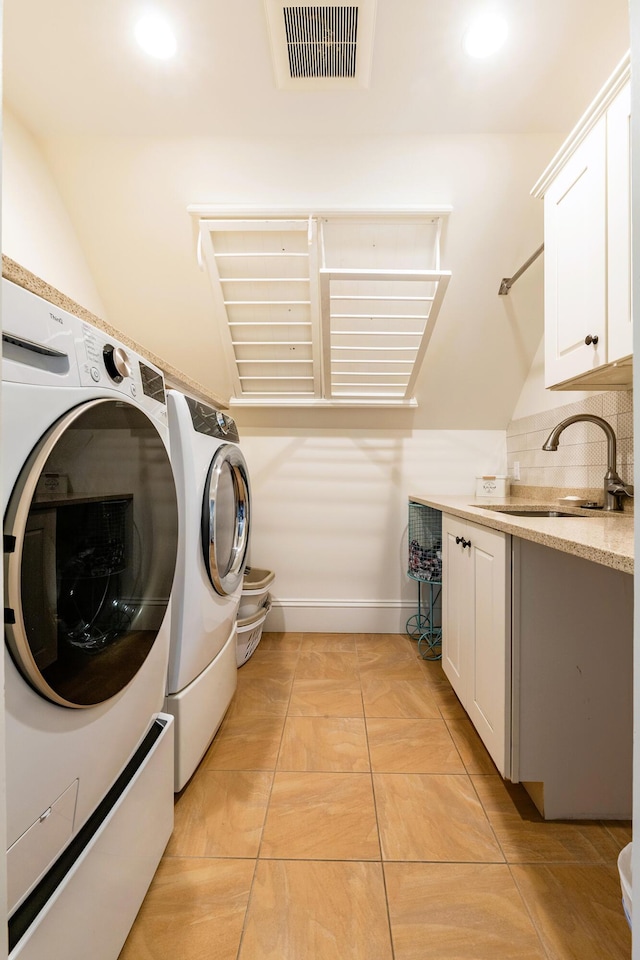 laundry area featuring light tile patterned flooring, cabinets, separate washer and dryer, and sink