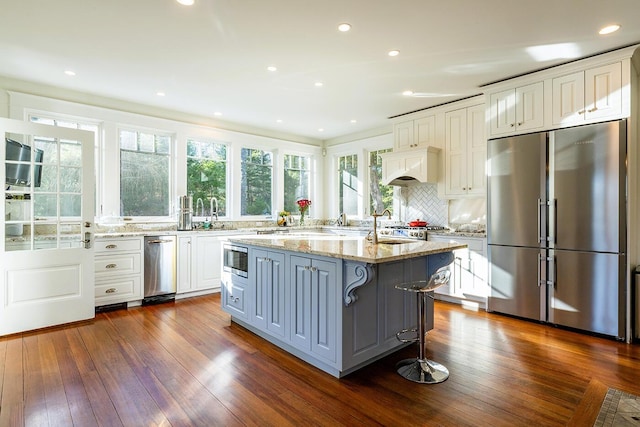 kitchen featuring white cabinets, a kitchen island, stainless steel appliances, and dark wood-type flooring