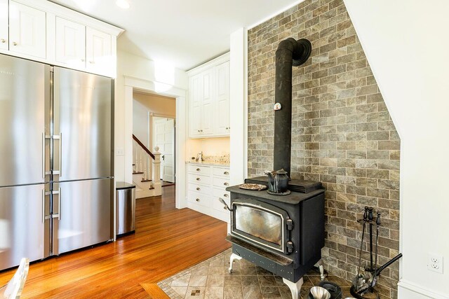 interior details featuring high end fridge, wood-type flooring, and a wood stove