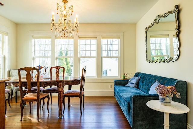 dining space with dark wood-type flooring, a healthy amount of sunlight, and an inviting chandelier