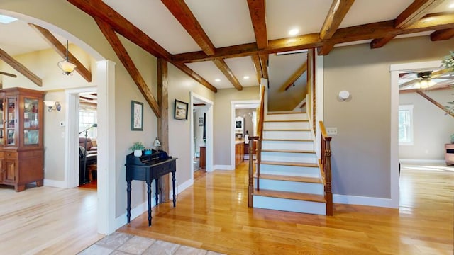 staircase with ceiling fan, beam ceiling, and wood-type flooring