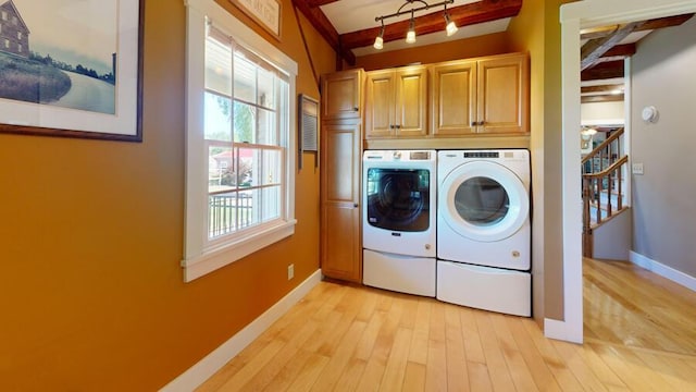 laundry room with cabinets, light hardwood / wood-style flooring, and washing machine and clothes dryer