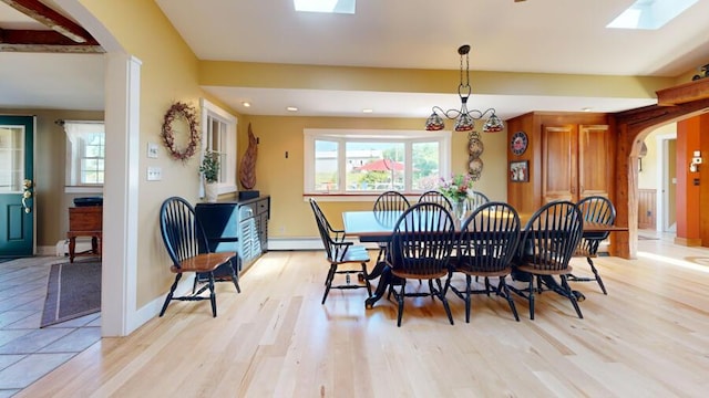 dining room featuring a chandelier, light wood-type flooring, and a skylight