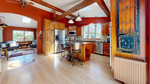 kitchen featuring a center island, radiator, hanging light fixtures, light hardwood / wood-style floors, and stainless steel appliances