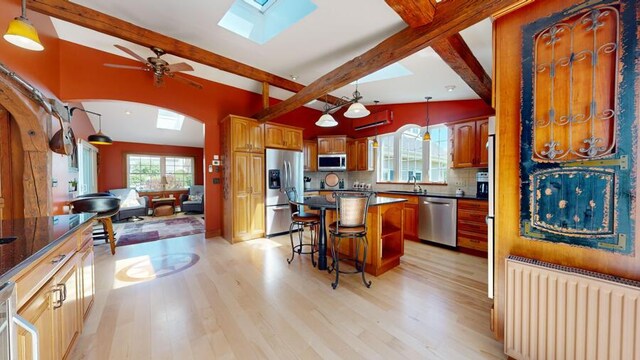 kitchen featuring radiator heating unit, stainless steel appliances, hanging light fixtures, and a kitchen breakfast bar