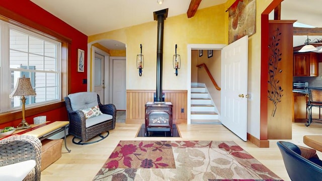 sitting room with lofted ceiling with beams, light hardwood / wood-style floors, and a wood stove