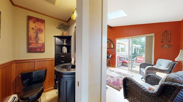 interior space with wooden walls, a skylight, crown molding, and a baseboard heating unit