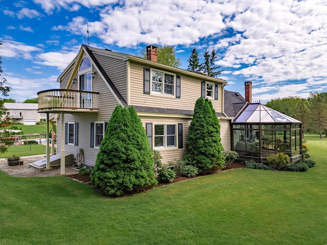 rear view of property with a lawn, a balcony, and a gazebo